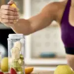 Mujer deportista preparando bebida nutritiva con limón para mejorar rendimiento en tenis - nutrición deportiva